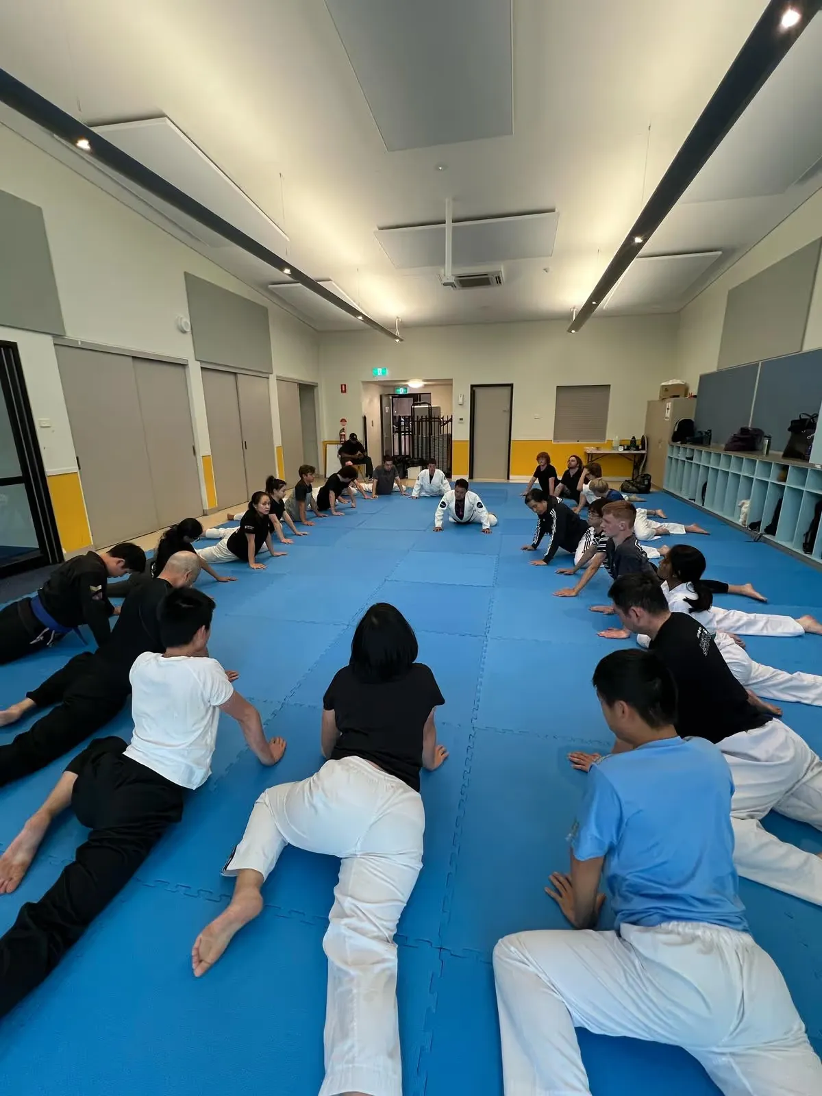 A beginners Brazilian Jiu Jitsu class warming up on the mat at Noble Grounds BJJ