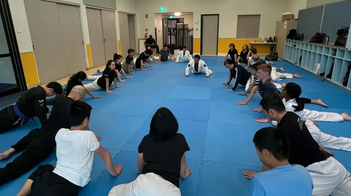 A class warming up in rows on the mats before training