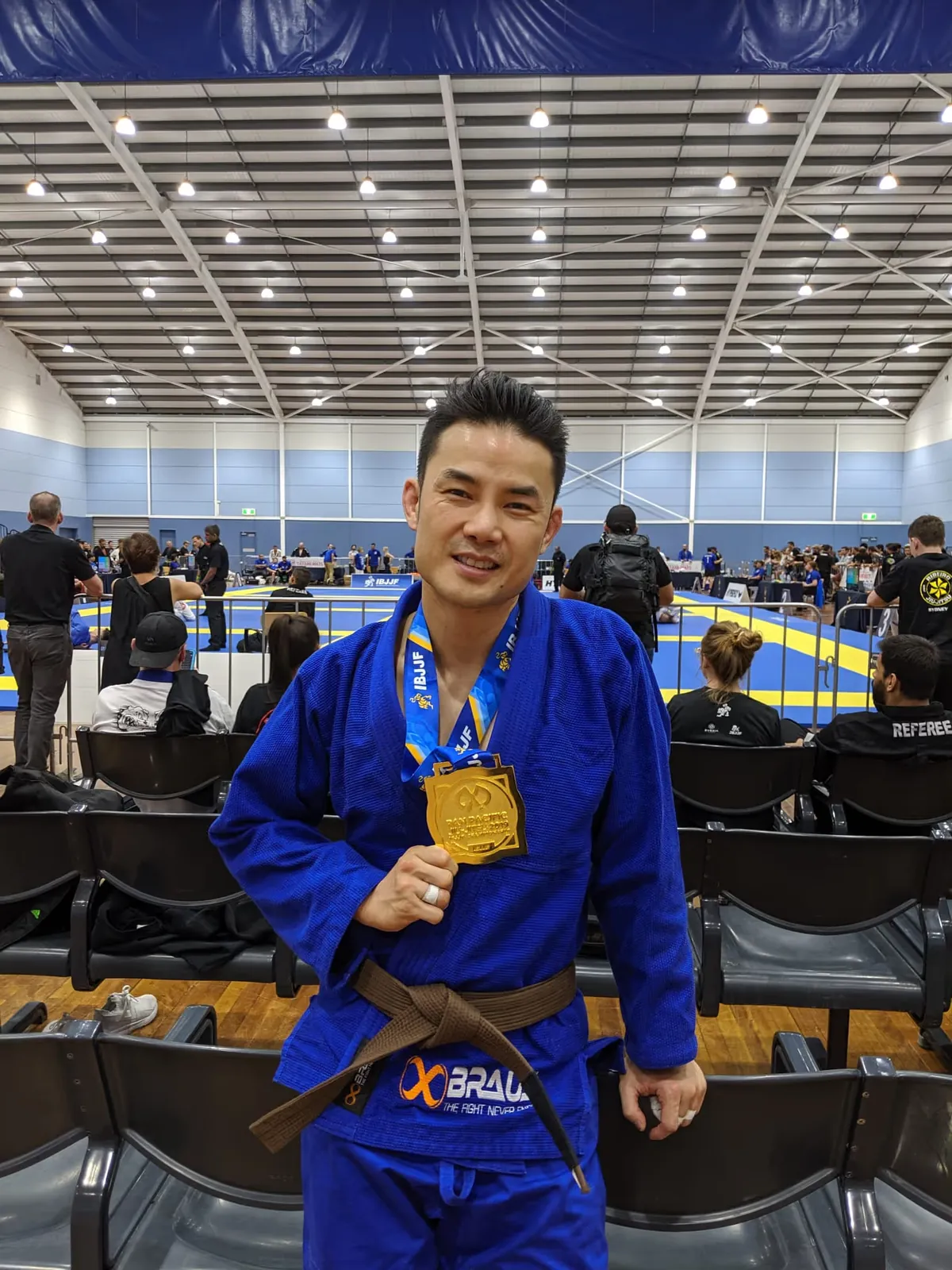Jason Ng, Head Coach at Noble Grounds BJJ, holding a gold medal at a Brazilian Jiu Jitsu competition